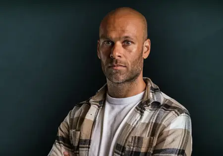 Renaldo Ishaak met armen over elkaar poserend bij groene achtergrond